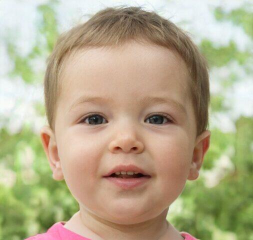 Adorable niño pequeño con cabello rubio y ojos grandes sonríe para la cámara.