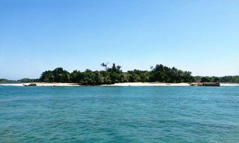 Isla tropical con playa de arena blanca y agua turquesa.