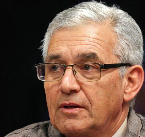 Retrato en primer plano de un hombre con cabello gris y gafas.