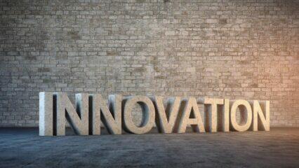 Representación 3D de la palabra INNOVACIÓN en piedra sobre una pared de ladrillo. Concepto de innovación abierta.