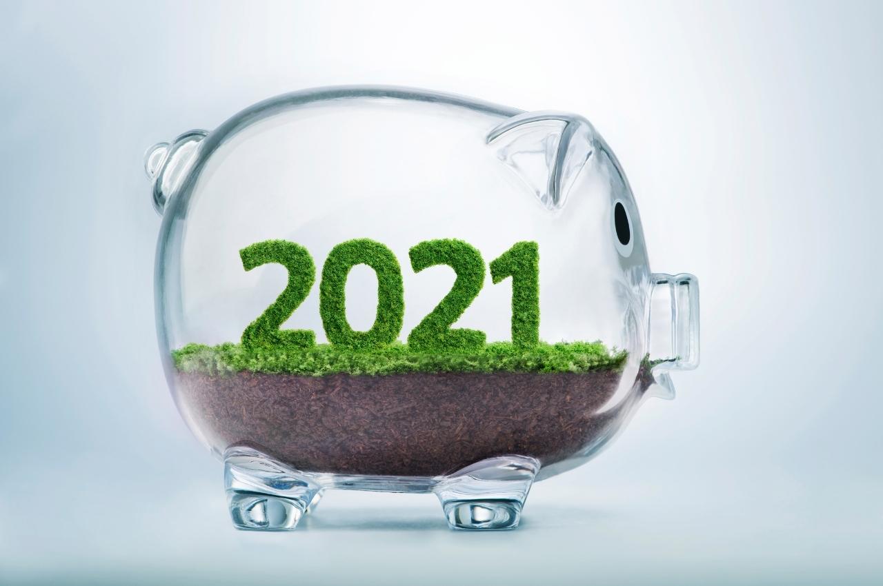 Alcancía de cristal con el año 2021 en hierba. Invirtiendo en el futuro.