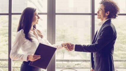 Socios comerciales se dan la mano cerca de una ventana, lo que significa una asociación exitosa.