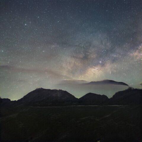 Galaxia, Vía Láctea, sobre montañas oscuras y silueteadas por la noche.